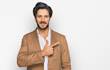 Young hispanic man wearing business clothes cheerful with a smile on face pointing with hand and finger up to the side with happy and natural expression