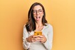 © Krakenimages.com - Young brunette woman using smartphone over yellow background winking looking at the camera with sexy expression, cheerful and happy face.