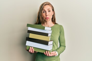 Poster - Young blonde woman holding a pile of books depressed and worry for distress, crying angry and afraid. sad expression.