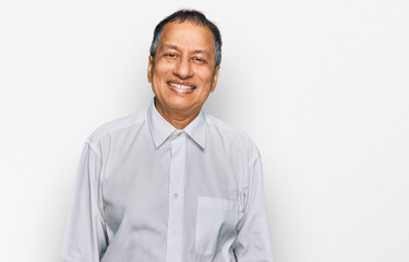 Wall Mural - Middle age indian man wearing casual white shirt looking positive and happy standing and smiling with a confident smile showing teeth