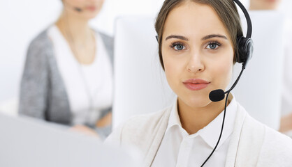 Wall Mural - Call center. Group of diverse operators at work. Beautiful woman in headset communicating with customers of telemarketing service. Business concept