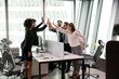 © fizkes - Overjoyed diverse multiracial businesspeople give high five engaged in teambuilding activity in office. Happy excited multiethnic colleagues employees celebrate shared team success or achievement.