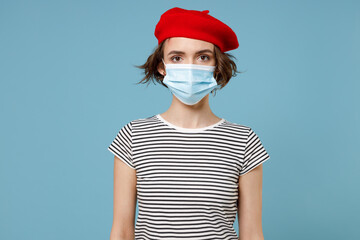 Wall Mural - Young woman 20s wearing french beret red hat striped t-shirt sterile face mask to safe from coronavirus virus covid-19 during pandemic quarantine isolated on pastel blue background studio portrait.