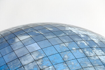 Glass spherical modern building with reflection of blue sky