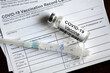COVID-19 vaccine bottle and syringe are on coronavirus Vaccination Record Card