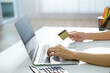 © amnaj - Close-up of woman shopping online using laptop pay by credit card at home.