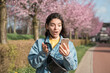 © Andrei - shocked face expression of a mixed races woman looking into the phone while walking on the street in bloomy spring