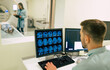 © My Ocean studio - Back view photo of a male doctor sitting near the computer and looking on patient in magnetic resonance imaging machine