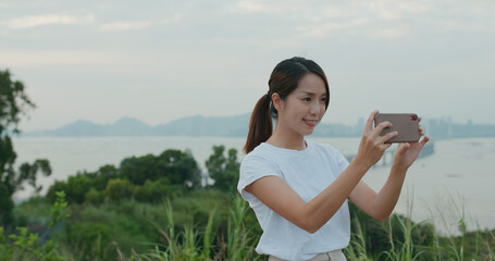 Poster - Travel woman use of cellphone to take photo on the top of the mountain