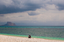 Altea Beach, With Some People In The Distance And With The Ifach Rock In The Background, On A Morning With Cloudy Skies 