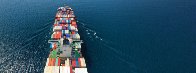 Wall Mural - Aerial drone ultra wide photo of huge container ship cruising deep blue open ocean sea near logistics container terminal port