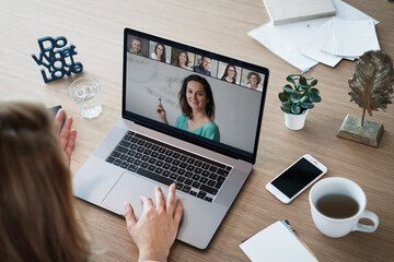 remote online working woman sitting on a work desk with laptop in in her home office joining an online meeting or watching video conference or webinar presentation