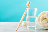 Fototapeta Sypialnia - A bamboo toothbrush, a glass of water, a white cotton towel and toothbrush powder in a jar. Biodegradable personal care products. No plastic concept