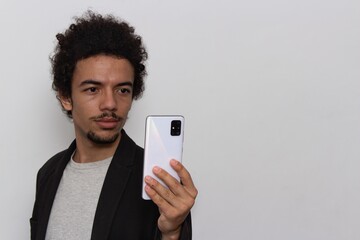 Man in black blazer on white background using cellphone