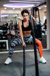 © shevtsovy - slim athletic woman working out with battle rope in gym. fitness female active. active multifunctional training workout indoors.