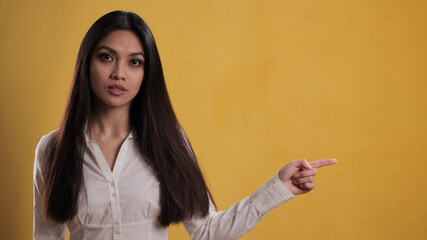 Wall Mural - Young pretty woman points to something - studio photography