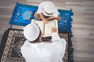 Muslim child learning to read Quran with his father