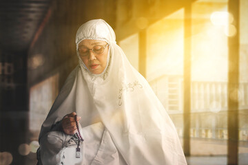 Muslim old woman holding prayer beads on mosque