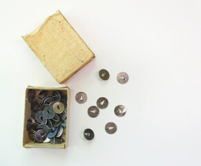 Stationery buttons are scattered from a box on a white background