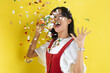 © faishalabdula - Beautiful young woman throwing confetti and looking happy on yellow background.