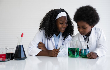 Education and research in lab concept. Happy african american student girl and boy is learning and test science chemical with colorful liquid in tube test and beaker in laboratory room at to school.