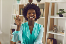 Friendly African American Business Woman Waving Her Hand In Greeting Over A Video Call. Female Worker Sits In Front Of A Webcam And Communicates During An Online Conference. Online Meetings Concept.