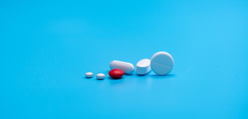 Poster - Group of round and oval white tablets pills, red sugar-coated tablets pills on blue background. Pharmacy shop and pharmacy department banner. Pharmaceutical industry. Health care. Drugs in daily life.