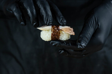 Close up of sushi chef hands preparing japanese food. Man cooking sushi at restaurant. Traditional asian seafood rolls on cutting board.