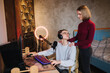 © Aleksandr - Young attractive wife help husband to work. Handsome man sits at the table and work on computer. Man using professional microphone and headphones