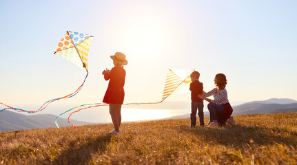 Poster - Happy family  mother and kids  launch  kite on nature at sunset