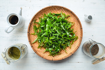 Poster - Green tea leaves in a wooden tray