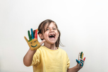 Happy toothless little girl with painted hands laughing and having fun - Little girl who is painting her hands with smiley faces and numbers - Childhood, colors and happiness concept - Copy space 