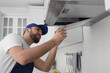 © New Africa - Worker repairing modern cooker hood in kitchen