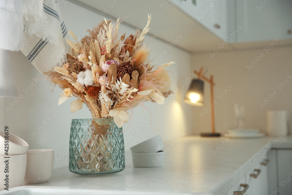 Bouquet of dry flowers and leaves on countertop in kitchen. Space for text - obrazy, fototapety, plakaty 
