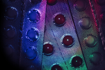 Fototapete - Pills or drugs in a package under neon light on a dark background pattern for design..