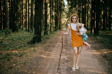 Wall Mural - Young mother with stick holding her son in the forest