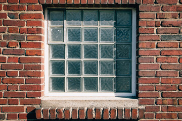 blue glass block window in red brick wall