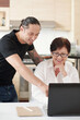 © DragonImages - Smiling mixed-race man explaining mother how to use new laptop and find useful information online