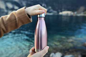 Close-up of female hand, open up the reusable, steel eco thermo water bottle. Copy space concept. Space for text. Plastic free.