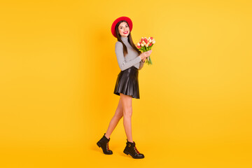 Poster - Full size profile side photo of happy woman walk hold spring flowers weekend isolated on yellow color background