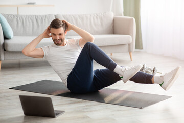 Athletic middle-aged man in sportswear doing crunches at home