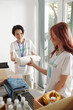 © DragonImages - Smiling young volunteers packing clothes and groceries and filling forms on laptop