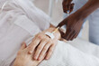 © Seventyfour - Close up of African-American male nurse setting up IV drip while caring for senior man in hospital, copy space