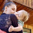 A young mother kisses her toddler son who has fallen asleep in her arms after a day of play. 