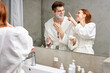 © Roman - interracial couple take care of facial skin, woman applying cream while man is going to shave stubble