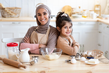 Wall Mural - Happy Islamic Mom And Little Daughter Posing In Kitchen While Baking Together