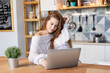 © deniskomarov - Modern girl with laptop computer at kitchen remote home office. Young blogger creating content for social networks, beautiful female freelancer working distantly.