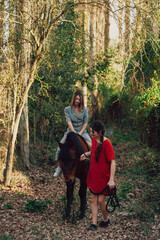 Wall Mural - Two women friends chatting and taking a ride with their horse through the countryside