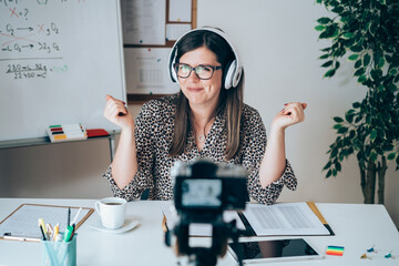 Wall Mural - Teacher recording video tutorial for e-learning class.
Female professor working from home teaching online using camera and headset for live streaming to 
physic student studying from home