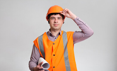 Wall Mural - Young construction worker in hard hat and reflective vest on grey studio background